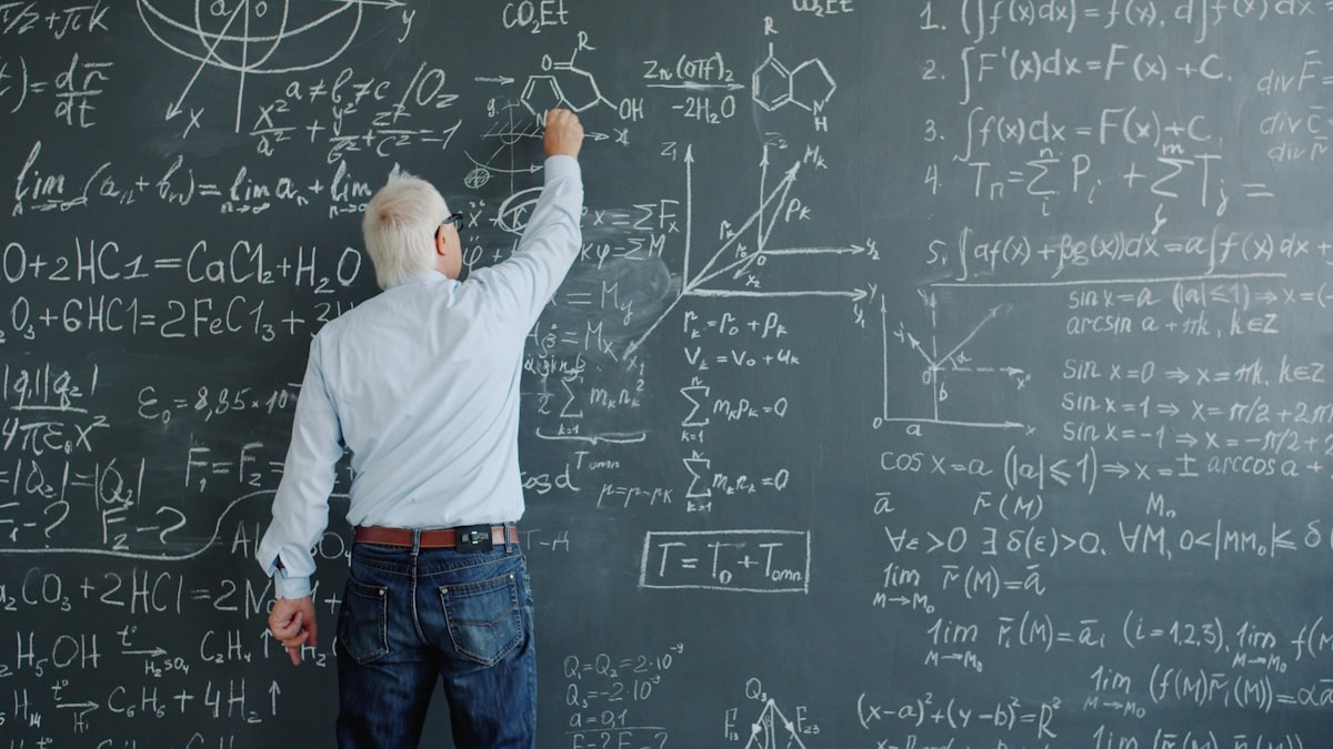 Teacher writing math formulas on a blackboard, representing the best AI tools for math teachers in 2026
