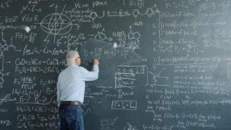 Professor writing complex equations on a blackboard.