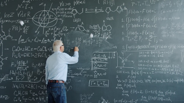 Professor writing complex equations on a blackboard.
