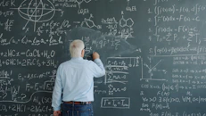 Elderly man writing complex equations on a chalkboard
