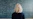 Woman with blonde hair facing a chalkboard with equations.