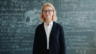 A woman stands in front of a chalkboard with equations.
