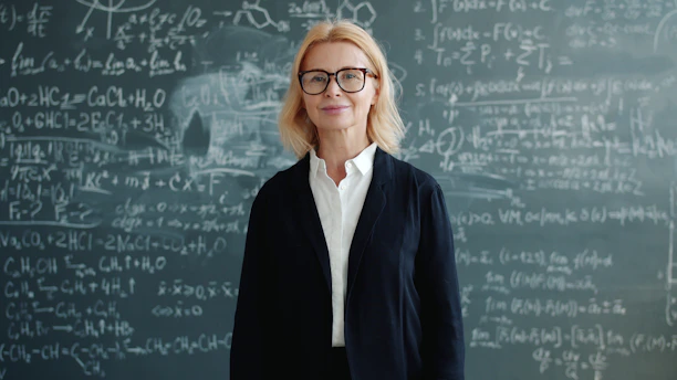 A woman stands in front of a chalkboard with equations