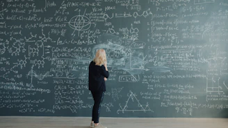 Woman in front of chalkboard with complex equations