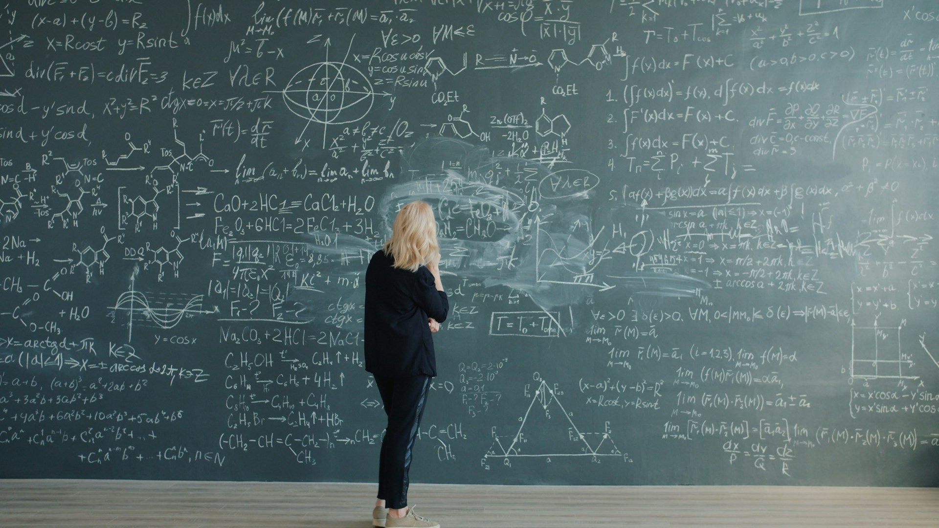 Woman in front of chalkboard with complex equations