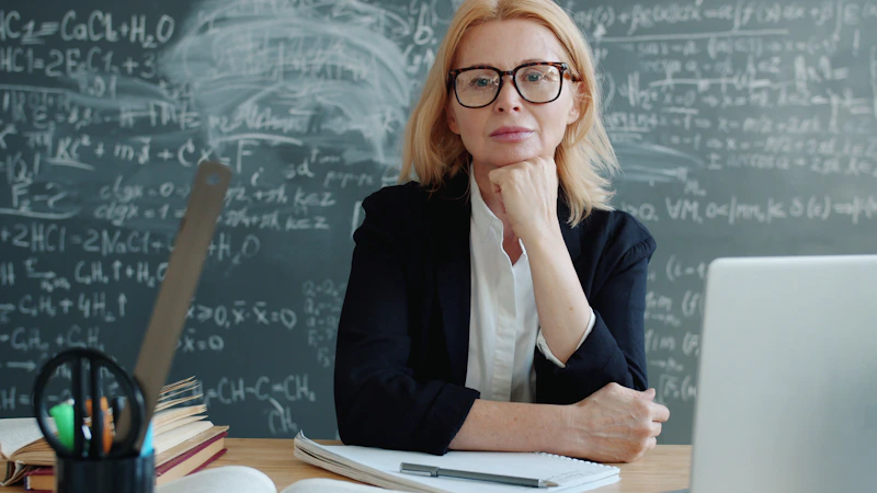 Profesora en escritorio con fórmulas matemáticas