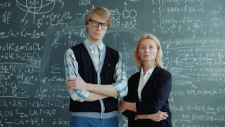 Two people stand in front of a chalkboard with equations.