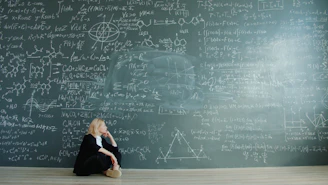 Woman contemplating complex formulas on a blackboard.
