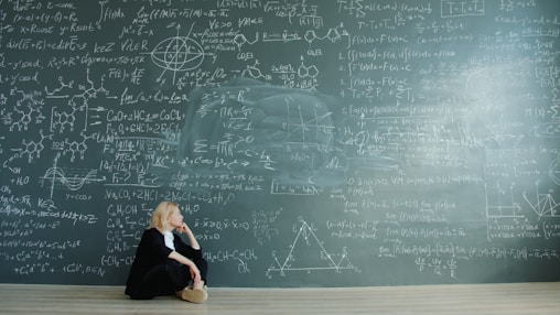 Woman contemplating complex formulas on a blackboard.