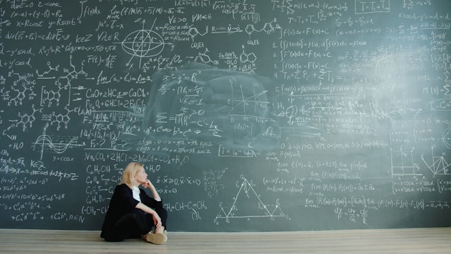 Woman contemplating complex formulas on a blackboard.