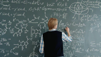 Teacher writing math equations on a chalkboard.