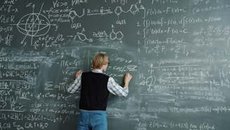 Student writing complex formulas on a chalkboard.