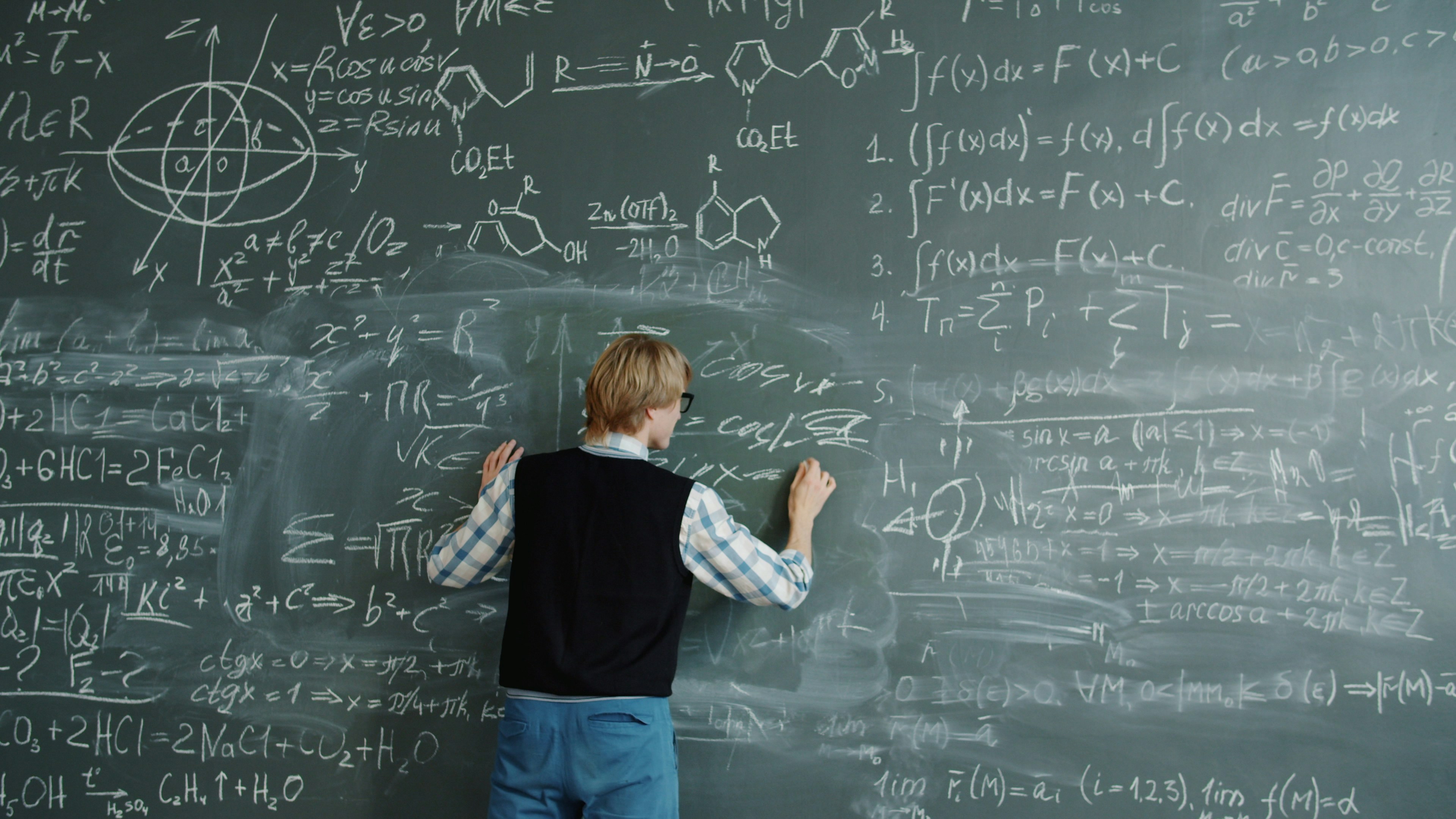 Crazy young man beating chalkboard yelling feeling angry because of science problem writing formulas. Education and negative emotions concept.
