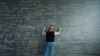 Student writing complex formulas on a chalkboard.