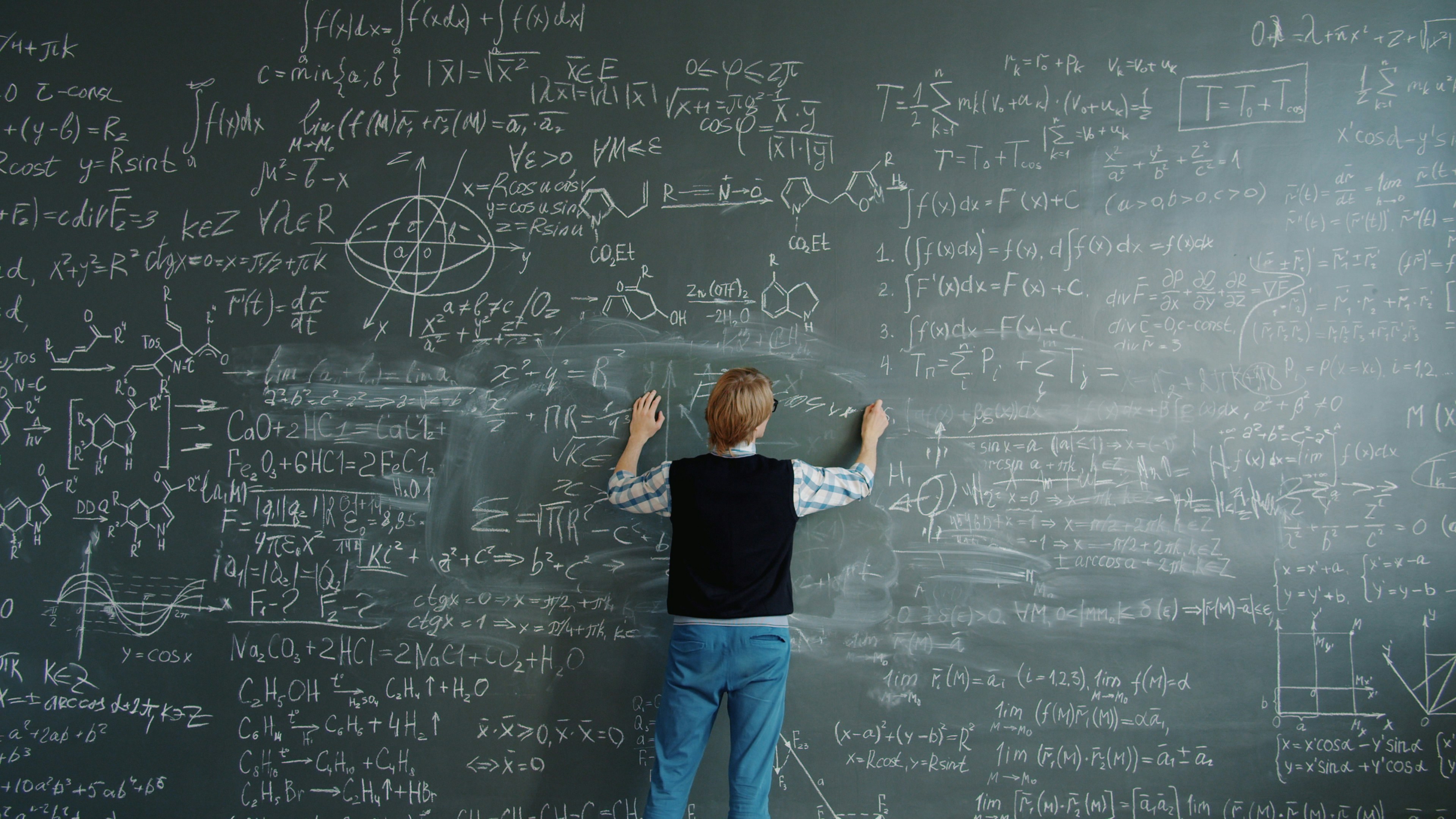 Crazy scientist is writing formulas on chalkboard then shouting beating board feeling angry because of science problem. Emotions, people and lifestyle concept.
