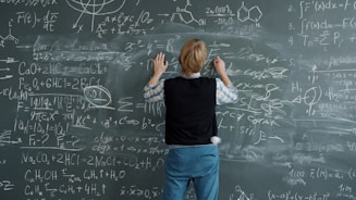 Student writing complex math equations on chalkboard