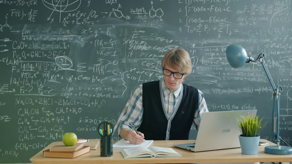 Student studying at a desk with a chalkboard in a virtual classroom setting