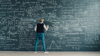 A person writing complex formulas on a chalkboard.