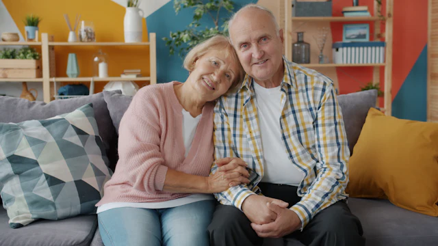 An older couple smiling warmly together on a couch at home
