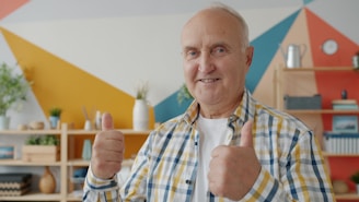 Smiling older man gives two thumbs up.