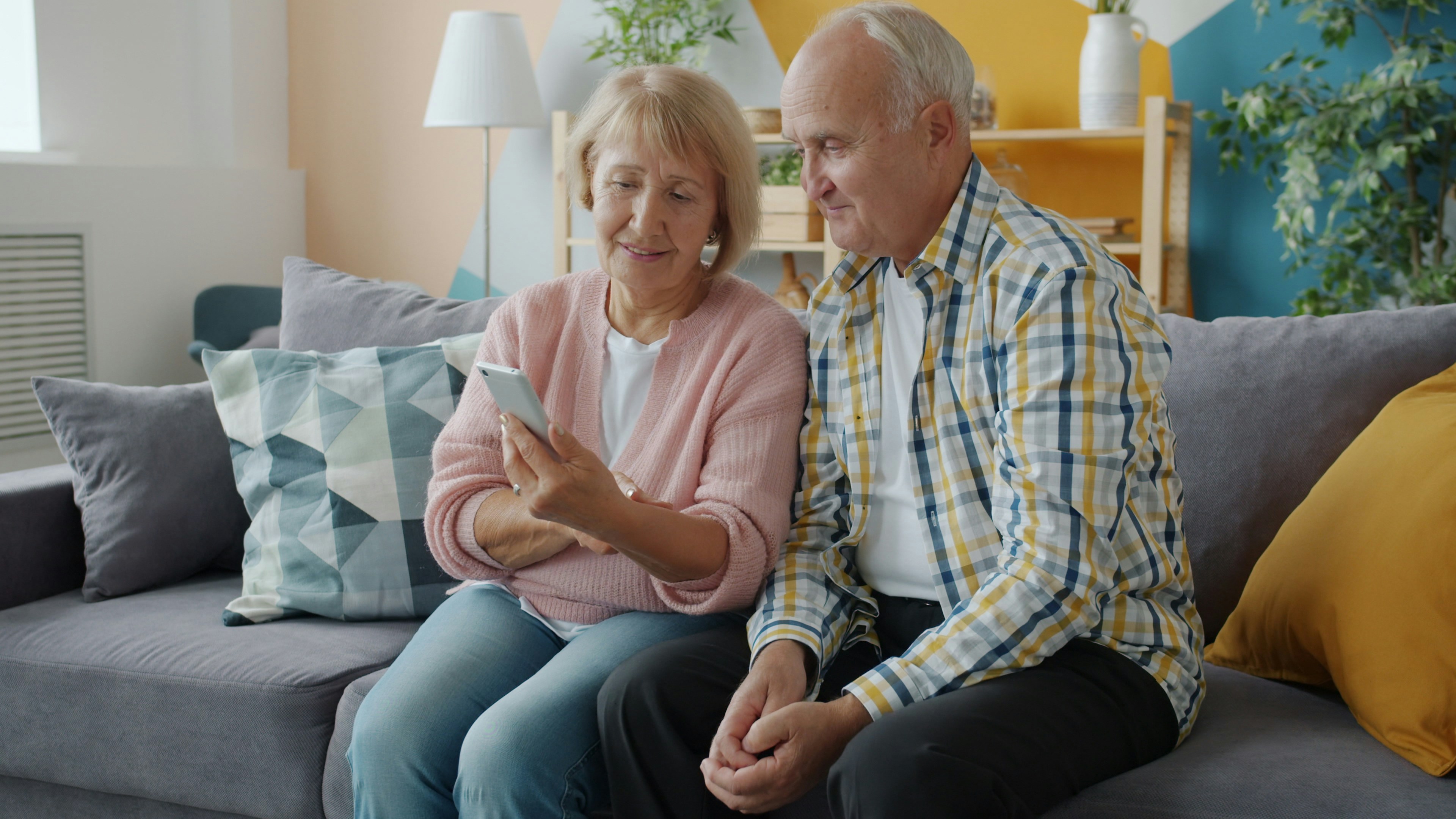 Two elderly people looking on a phone together