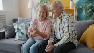 Elderly couple looking at a smartphone together on couch.