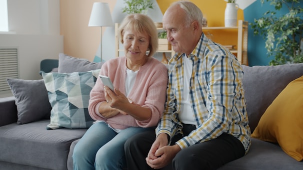 Elderly couple looking at a smartphone together on couch.