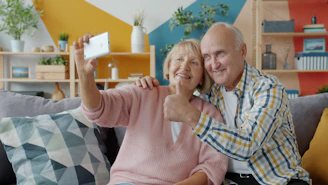 Elderly couple taking a selfie on the couch