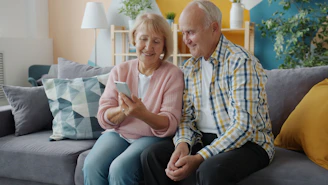 Elderly couple looking at a smartphone together on sofa