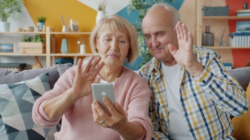 Elderly couple waving at smartphone screen
