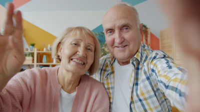 Elderly couple waving hello on a video call.