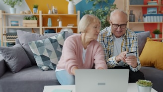 Elderly couple shopping online with credit card and laptop.