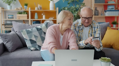 Elderly couple shopping online with credit card and laptop.