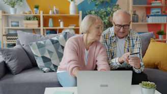Elderly couple shopping online with credit card and laptop.