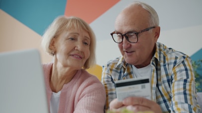Elderly couple looking at laptop with credit card