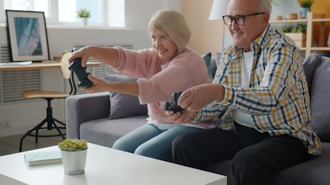 Elderly couple playing video games together on couch