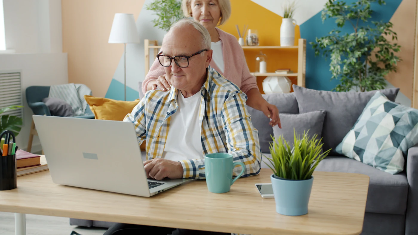 A couple at home looking at a laptop together in a bright living room