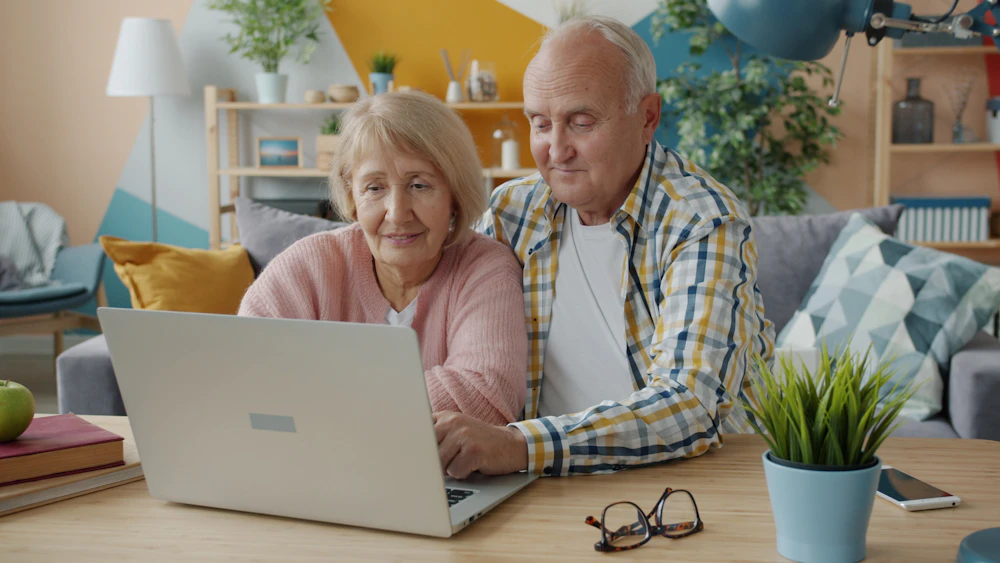 An older couple looking at a laptop together at home