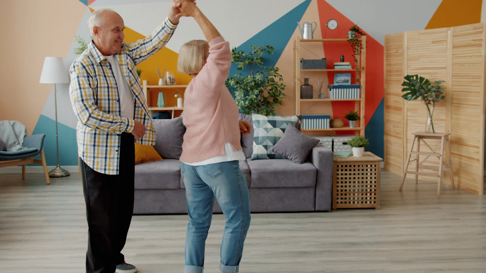 An elderly couple dancing joyfully together in their living room