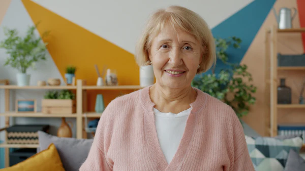 An elderly woman smiling warmly in her living room