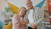 Elderly couple smiling together in a colorful room.