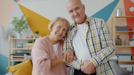 Elderly couple smiling together in a colorful room.