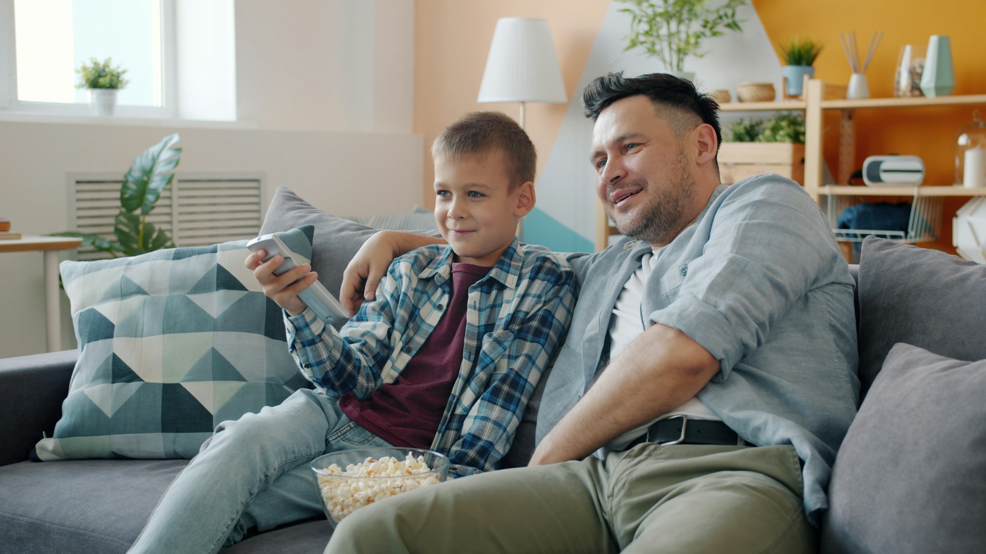 Father and son watching television together on couch.