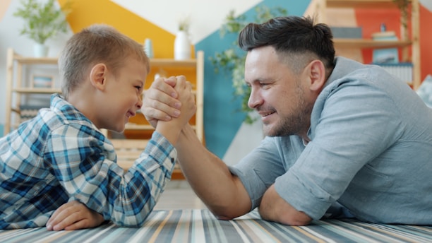 Father and son arm wrestling on the floor
