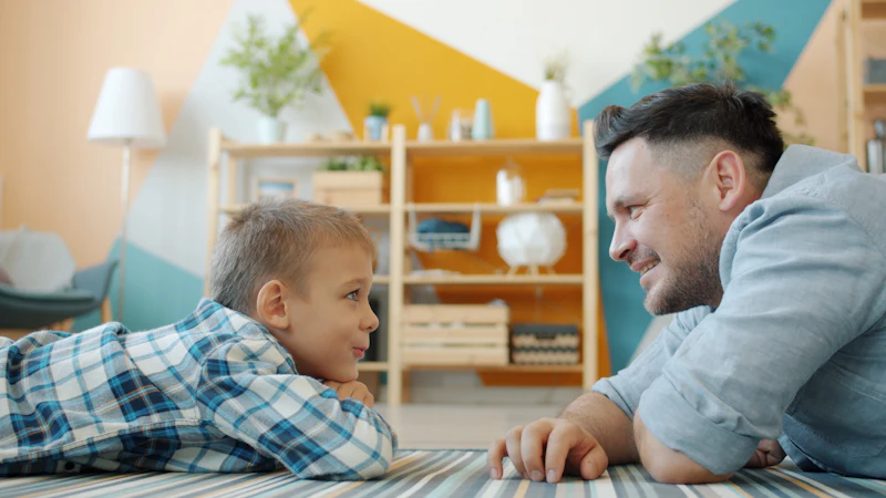 Father and son looking at each other, sitting on the floor