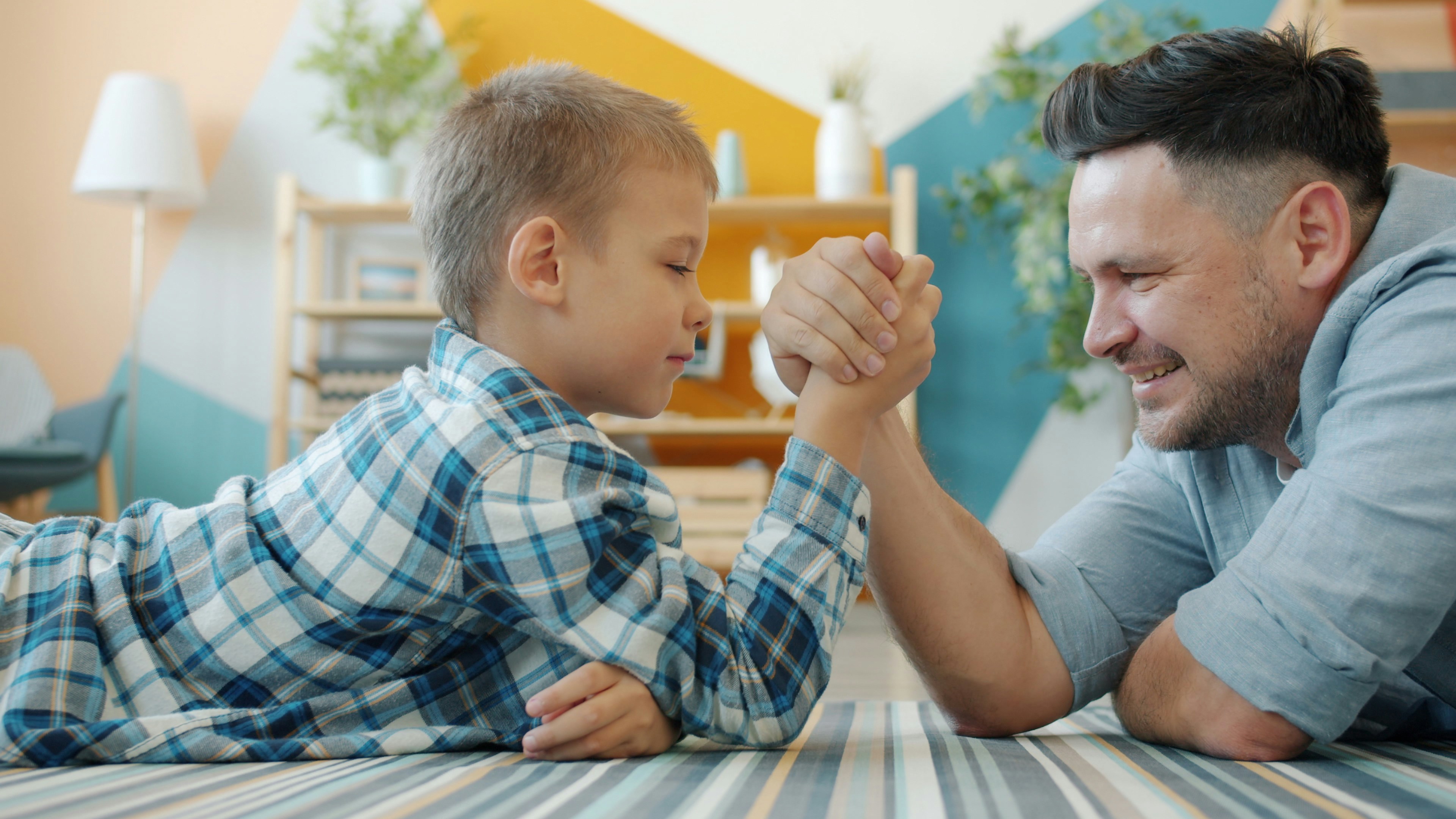 Father and son arm wrestling on the floor