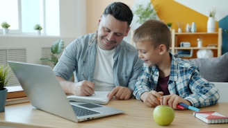 Father and son studying together at a desk.