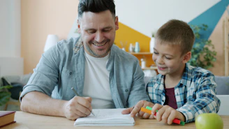Father and son drawing together at a table.