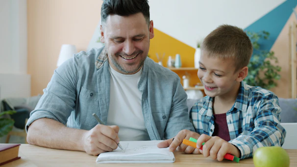 Father and son drawing together at a table.