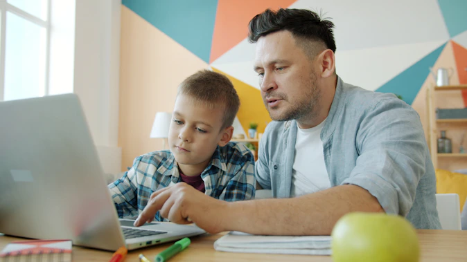 Father and son learning together on a laptop.